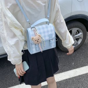 Detailed side view of light blue checkered mini backpack with brown plush bear charm