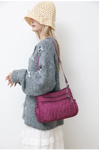 Detail of fuchsia nylon crossbody bag with heart pattern quilting and multi-zipper pockets