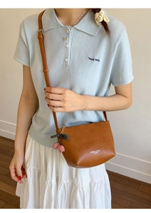 Brown leather bucket bag detail with cherry pendant and adjustable shoulder strap