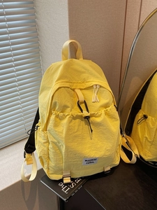 Minimalist bright yellow nylon backpack with front pocket and waswac rules logo label