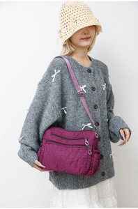 Detail of purple nylon crossbody bag featuring heart-shaped quilting and zipper pockets