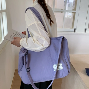 Macro shot of purple canvas tote bag featuring adjustable strap and woven brand label