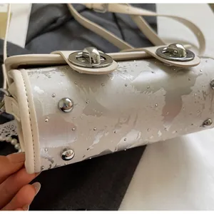 Détail du sac beige à motif mappemonde avec pieds en métal et fermoir rotatif argenté