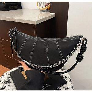 Detail of a black crescent bag with white contrast stitching and silver chain strap
