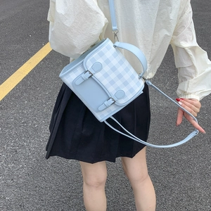 Detail of light blue gingham crossbody bag with adjustable strap and metal buckles