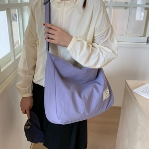 Detailed side view of purple canvas messenger bag with wide shoulder strap on model