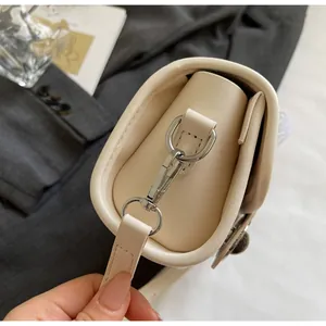 Détail du crochet en métal argenté et coutures soignées sur sac à main en cuir beige