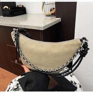 Detail of beige crescent bag with metallic chain strap and suede texture finish