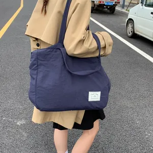 Detailed view of dark blue nylon tote bag featuring wide shoulder straps and textile label