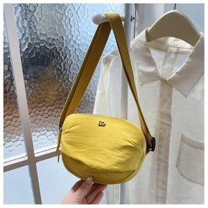Detailed close-up of a vibrant yellow nylon crossbody bag with metallic D-logo decoration