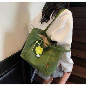 Dettaglio della borsa tote in tela verde con ciondolo a girasole e ampio interno