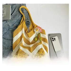 Detail of crochet striped shoulder bag with floral pendant on flat lay background