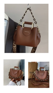 Detail view of brown leather bucket bag with metal chain and wide lettered strap