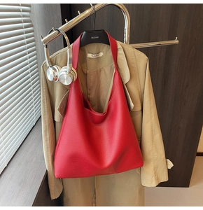 Dettaglio della borsa hobo rossa con trama litchi appesa con abiti alla moda