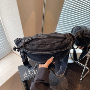 Close-up of black denim sling bag with metal zipper and wide adjustable strap details