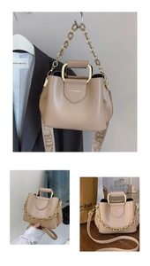 Detail of beige leather bucket bag with gold handle, metal chain and wide fabric strap