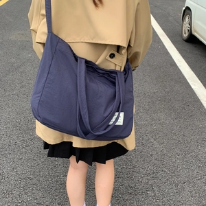 Rear view of model wearing a large navy blue canvas crossbody tote bag on city street