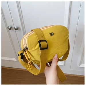 Detail of yellow nylon crossbody bag with multiple zippers and wide fabric strap