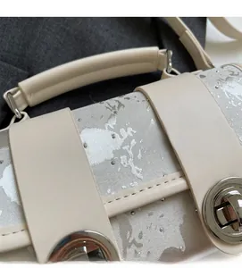 Détail du sac à main beige avec motifs floraux argentés et fermoir en métal argenté