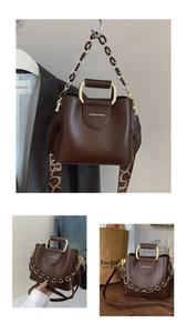 Detail of dark brown leather tote bag with golden U-shaped handles and decorative chain
