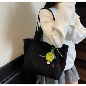 Dettaglio della borsa tote in tela nera con ciondolo a girasole ed etichetta