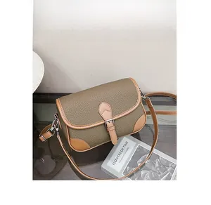 Detail of olive green litchi grain leather bag with brown trim and silver hardware