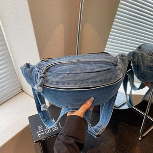 Close-up of crescent denim crossbody bag with vintage wash and distressed fringe details