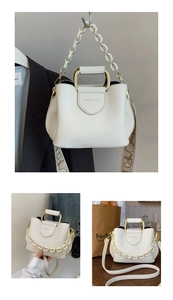 Detailed view of cream leather bucket bag with gold handle, chain, and embossed logo