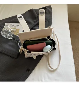 Détail de l'intérieur d'un sac à bandoulière beige montrant le rangement du mobile