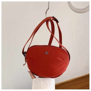 Detailed view of an orange crescent nylon crossbody bag featuring a silver metal DD logo buckle