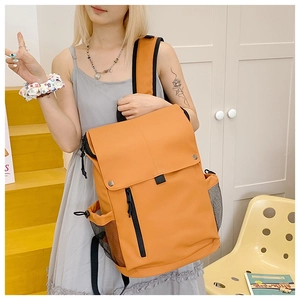 Vue détaillée d'un sac à dos en toile orange avec boucle métallique et poches latérales filet