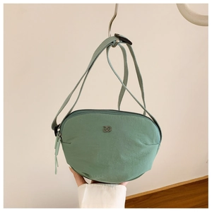 Close-up of mint green nylon crossbody bag showing the DD metal logo and fabric strap