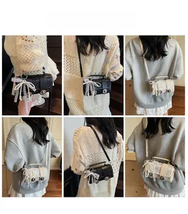 Détail du mini sac cylindrique avec nœud en dentelle et perle porté par un mannequin