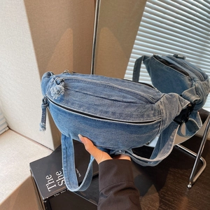 Detailed macro view of durable blue denim chest bag with metallic zipper and fringe tassels