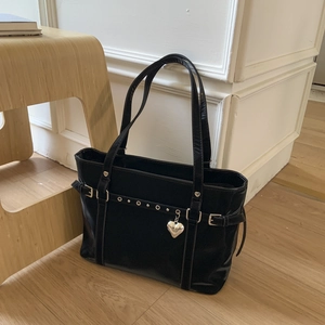 Detail of black glossy leather tote bag with silver heart charm and buckles