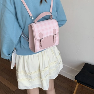 Detail view of pink plaid backpack with adjustable leather straps and decorative buckles