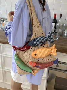 Chic beige knit tote bag with colorful plush fish charms for casual vacation style