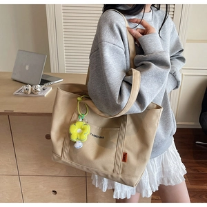 Vista dettagliata della borsa tote in tela beige con tracolla e ciondolo a girasole