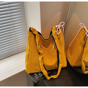 Détail du cabas en nylon jaune avec bandoulière plissée et cordon rose de serrage