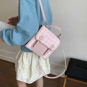 Detail of pink and white checkered satchel featuring double buckles and leather handle