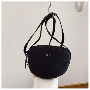 Detail of black nylon crescent crossbody bag featuring silver DO metal logo and strap