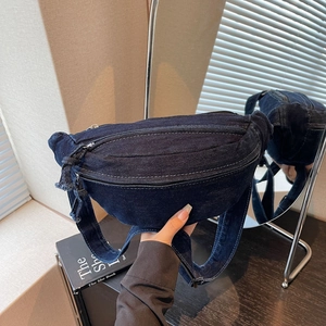 Close-up of deep blue denim crossbody bag with white stitching and adjustable strap