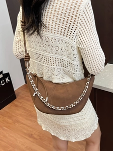 Brown suede half-moon crossbody bag with silver chain detail and knotted strap