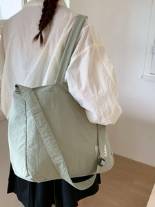 Large sage green canvas tote bag with adjustable shoulder strap and woven label detail