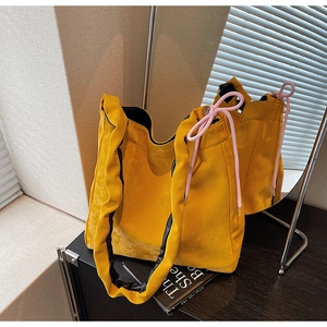 Vue macro d'un sac cabas plissé jaune avec cordon rose et texture douce aspect daim