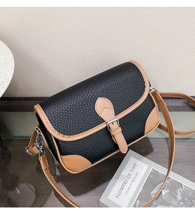 Detail of cross-body bag featuring black lychee leather and brown smooth trim accents
