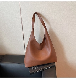 Dettaglio macro della pelle marrone martellata e del manico della borsa hobo moderna