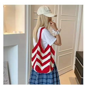 Detail of red and white striped hand-knitted hobo bag with textured crochet weave patterns