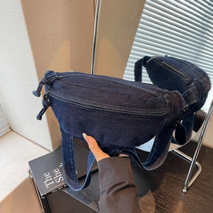 Detailed close-up of dark blue denim waist bag with visible stitching and metal zipper