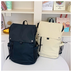 Détail de sacs à dos grande capacité noirs et beige avec boutons pression et poches filet